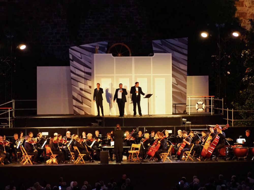 Die Solisten vor dem Bühnenbild mit dem Orchester nach Sonnenuntergang