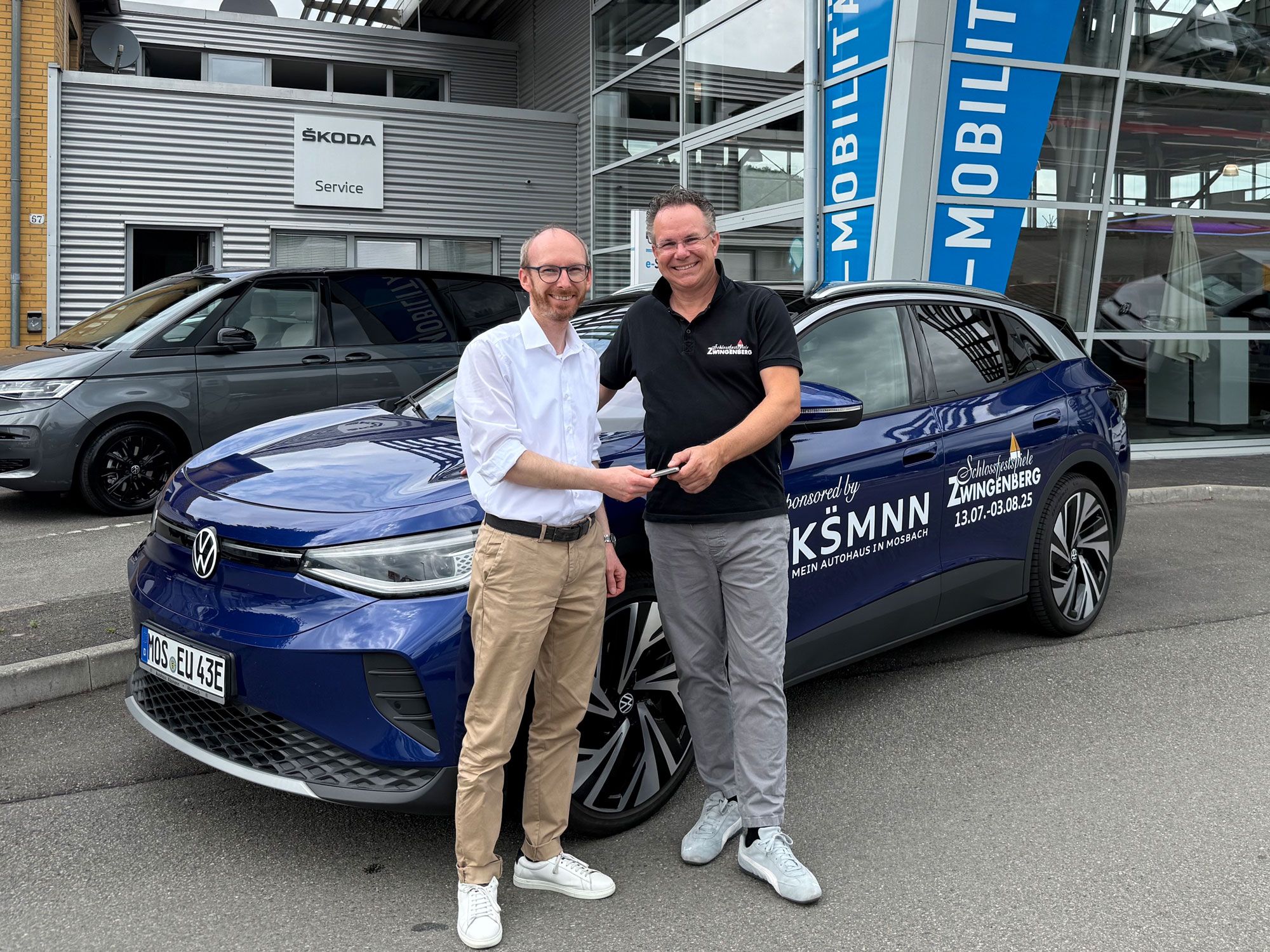 Zwei Männer bei der Übergabe eines Autos